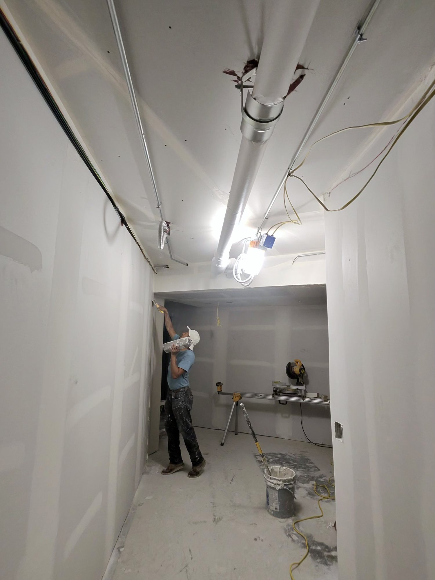 Patch and Paint Bros crew member taping a ceiling seam on a ladder