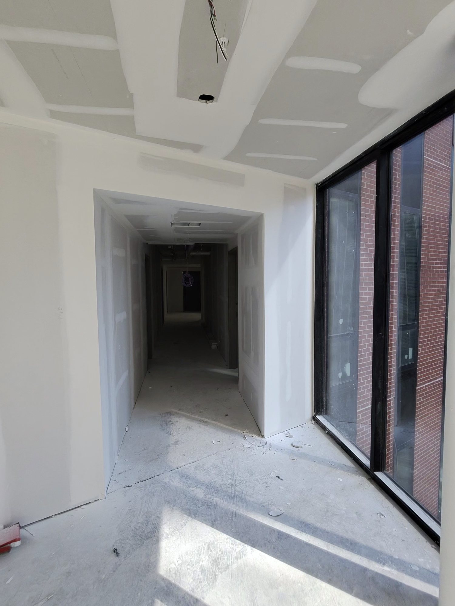 Taped and sanded hallway in a downtown high-rise, large window at the end